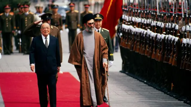 El presidente chino Yang Shangkun (1907 - 1998) (centro izquierda) y el presidente iraní Ali Khamenei (centro derecha) caminan juntos durante una ceremonia de bienvenida para la visita de Estado de este último, Beijing, China, 11 de mayo de 1989.