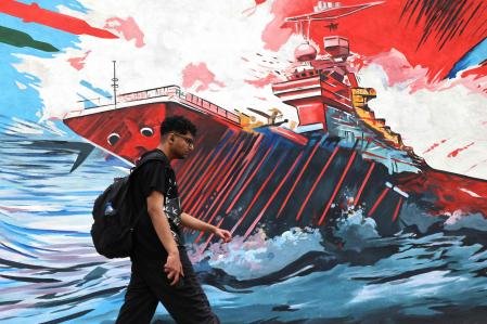 Un iraní pasa por delante de un mural antiestadounidense y antiisraelí en el centro de Teherán en la víspera de que expire el alto el fuego