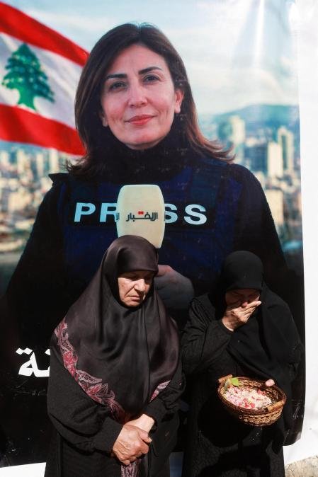 Dos mujeres en duelo permanecen frente a un retrato de la periodista Amal Khalil, quien murió en un ataque israelí el miércoles