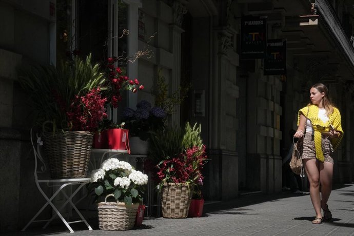 Barcelona amanece entre paradas de libros y rosas y espera superar las ventas de 2025 Una chica pasa por delante de una floristería mirando las rosas expuestas en la puerta