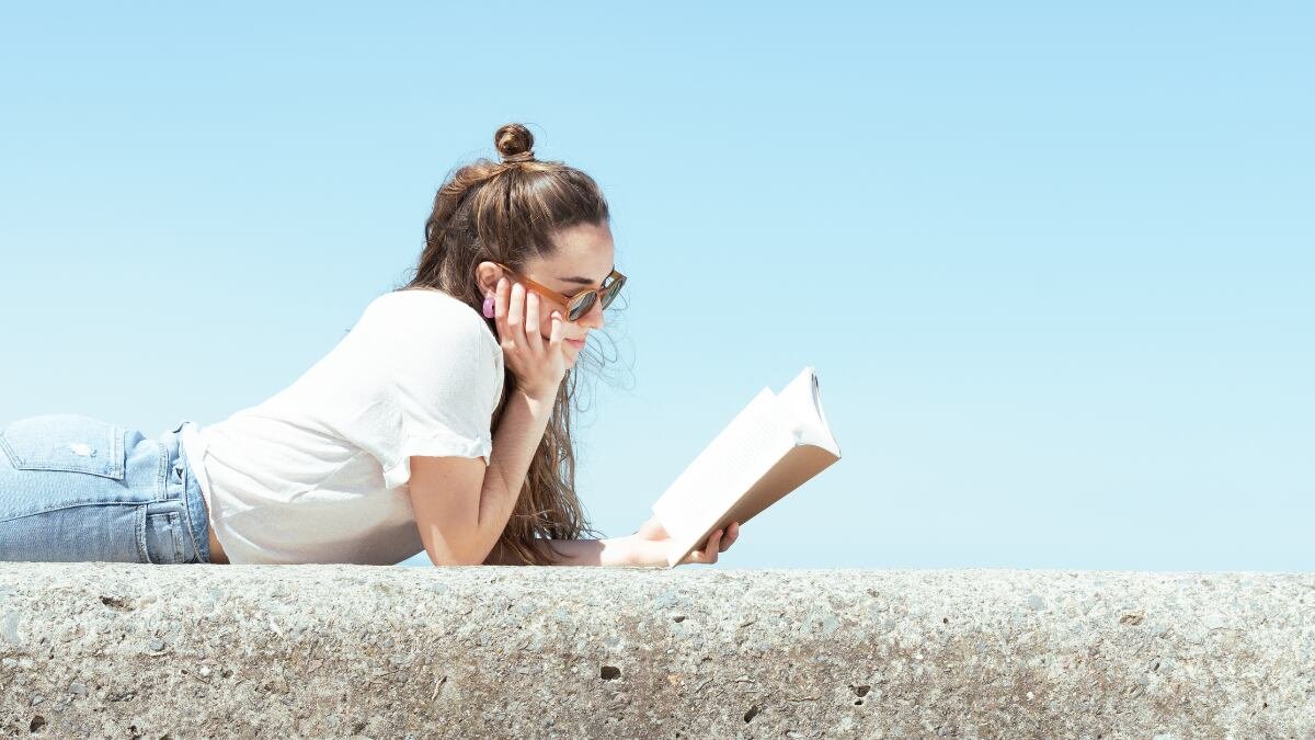 Una mujer lee un libro al aire libre.