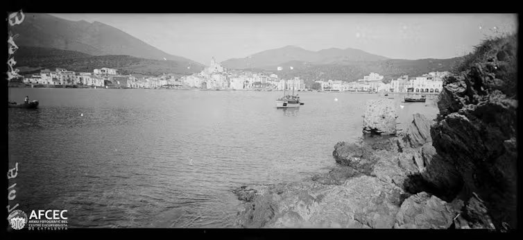 Fotografía en blanco y negro de una bahía con un pueblo costero al fondo.