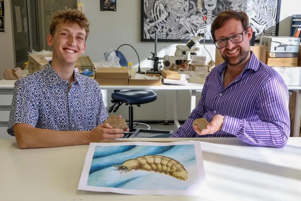 Thomas Turner y el paleontólogo Russell Bicknell posan junto a una reconstrucción artística de Magnicornaspis garwoodi, el artrópodo que habitó los mares hace unos 500 millones de años