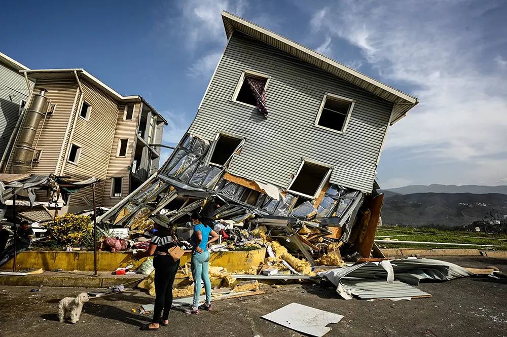 <p>Mujeres se paran cerca de los restos de un edificio dañado tras los terremotos en La Guaira, Venezuela, el 25 de junio de 2026 - REUTERS/ MAXWELL BRICEÑO</p>
