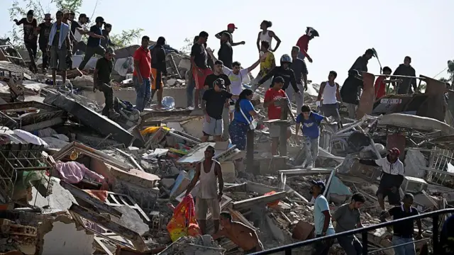 Personas buscan supervivientes mientras otras intentan rescatar pertenencias de un edificio colapsado tras un terremoto en Catia La Mar, estado de La Guaira, el 25 de junio de 2026.