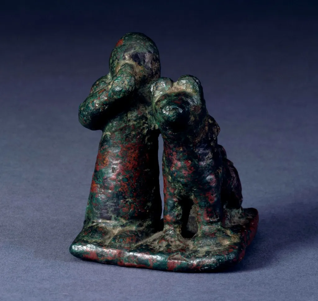 Estatuilla neoasiria de bronce con una figura humana y un perro